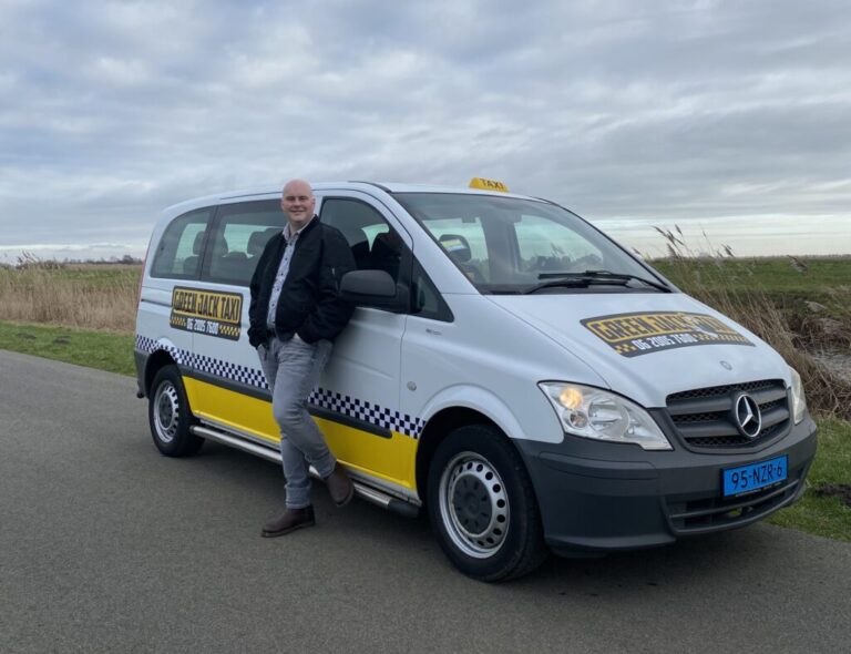 Professionele taxichauffeur staat bij gele Mercedes Vito taxi voor personenvervoer en vliegveldtransport