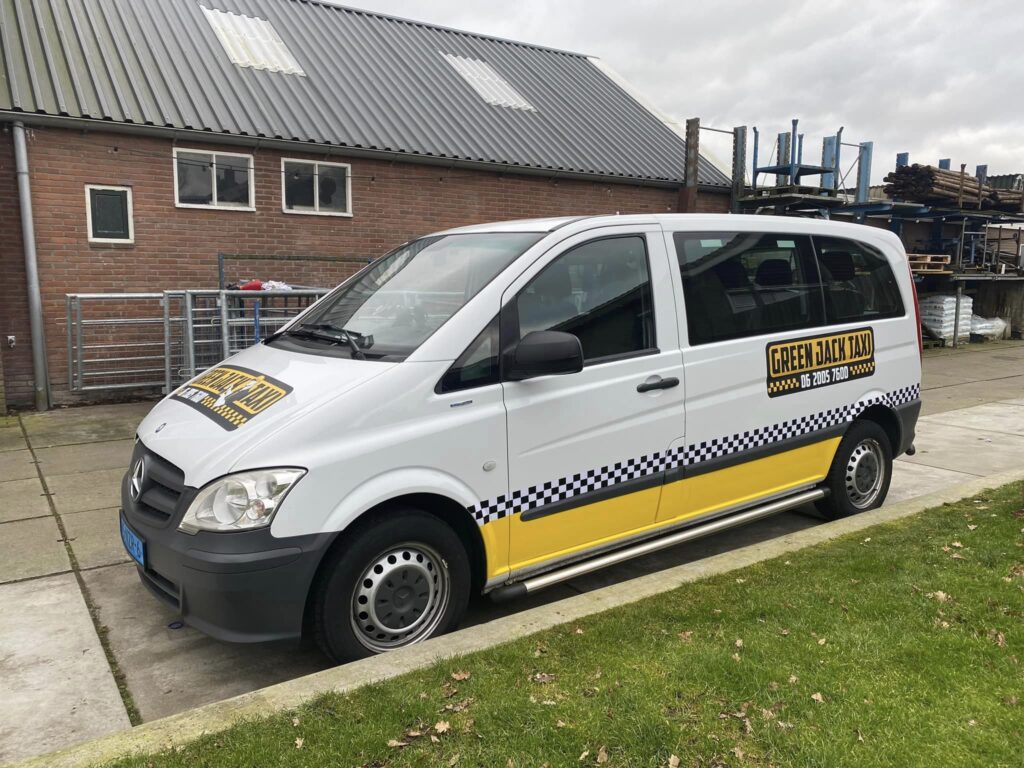 Witte Mercedes taxi van Taxi Jack geparkeerd voor bedrijfspand, professioneel personenvervoer
